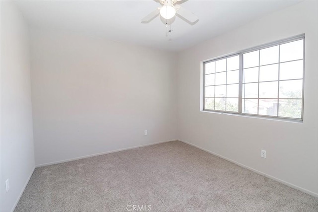 carpeted empty room with baseboards and a ceiling fan