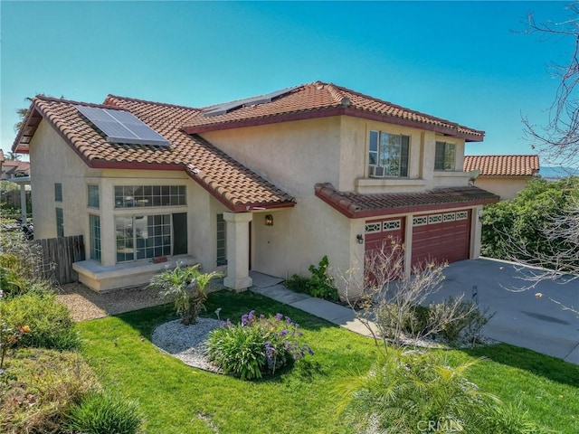 mediterranean / spanish-style home featuring fence, a tile roof, roof mounted solar panels, stucco siding, and an attached garage