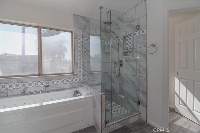 bathroom featuring a jetted tub, wood finished floors, and a shower stall