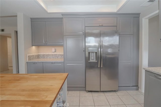 kitchen featuring stainless steel fridge, light tile patterned flooring, and gray cabinets