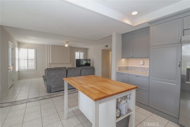 kitchen with gray cabinets, open floor plan, light tile patterned flooring, butcher block counters, and ceiling fan