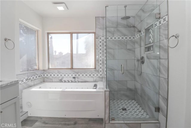 full bathroom with wood finished floors, a tub with jets, a stall shower, and vanity