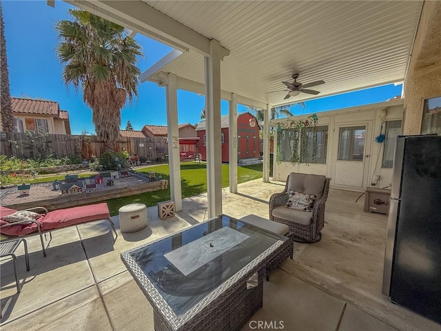 view of patio featuring an outdoor structure, a fenced backyard, a ceiling fan, and outdoor dining space