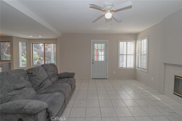 living area featuring light tile patterned floors, a fireplace, baseboards, and ceiling fan