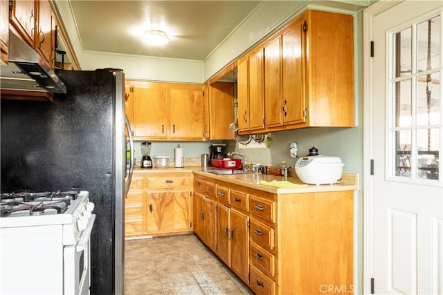 kitchen with brown cabinets, gas range gas stove, light countertops, under cabinet range hood, and a sink