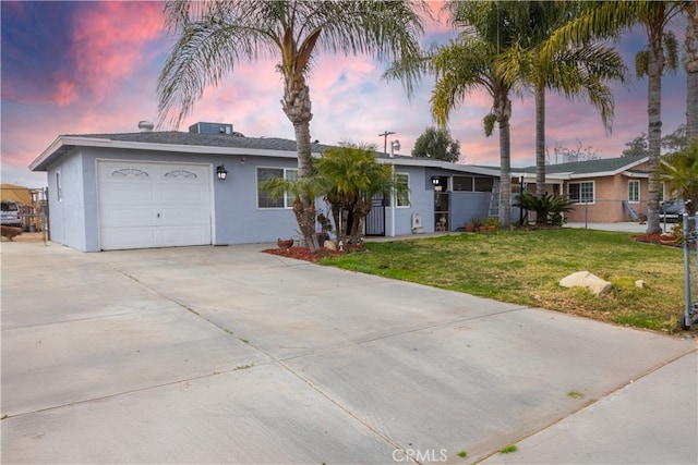 ranch-style house featuring a garage, a lawn, concrete driveway, fence, and stucco siding