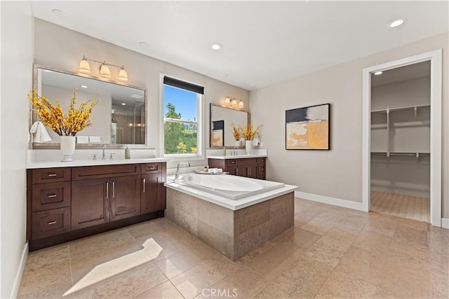 full bathroom with recessed lighting, a sink, two vanities, baseboards, and a bath