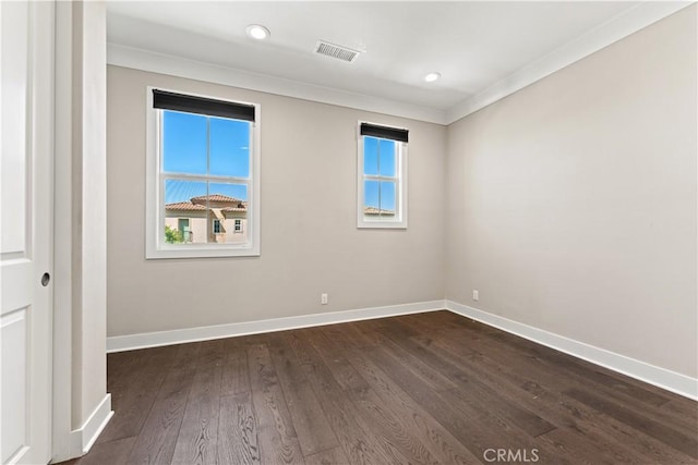 spare room featuring dark wood-style flooring, recessed lighting, visible vents, ornamental molding, and baseboards