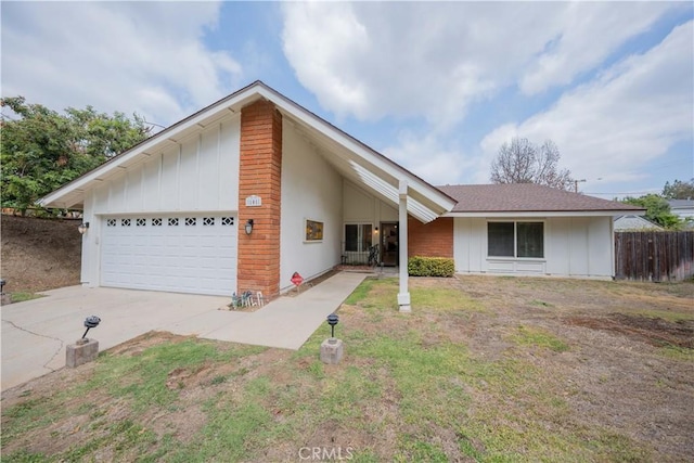 view of front of home with concrete driveway, board and batten siding, an attached garage, and fence