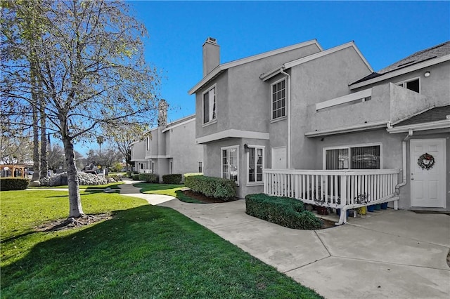 exterior space with a front yard, a chimney, and stucco siding