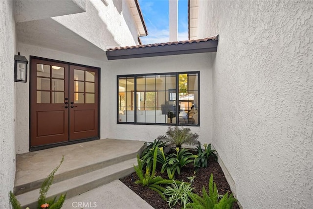 doorway to property featuring french doors, a tile roof, and stucco siding