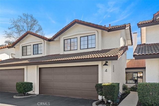 view of front of property with a garage, driveway, a tiled roof, and stucco siding