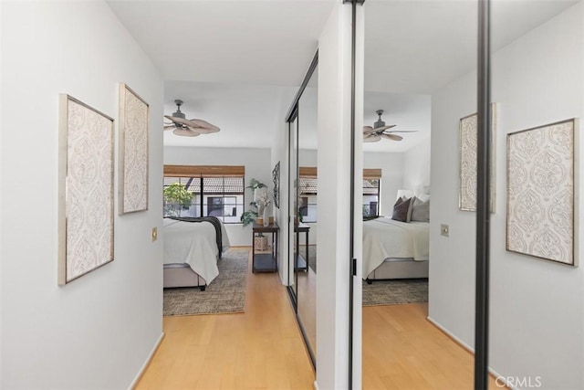 hallway featuring light wood-style flooring and baseboards