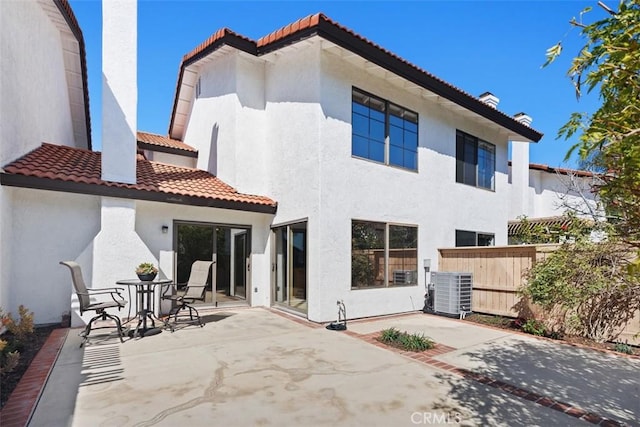 back of property with a tile roof, a patio, stucco siding, fence, and cooling unit