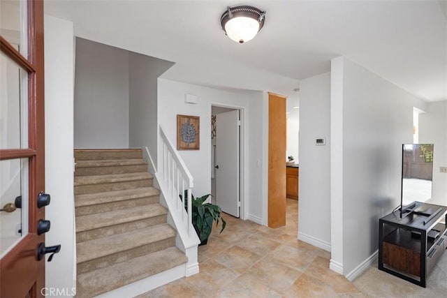 foyer entrance with baseboards and stairs