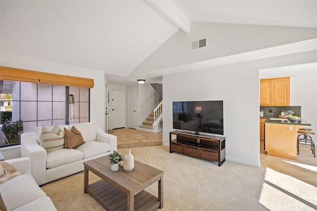 living room with beam ceiling, light colored carpet, visible vents, stairway, and high vaulted ceiling