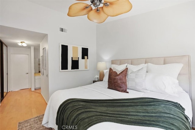 bedroom featuring ensuite bathroom, wood finished floors, visible vents, and a ceiling fan