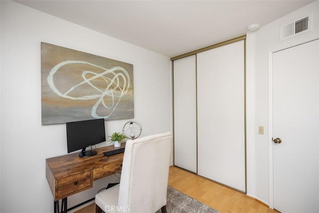 office area with light wood-style floors and visible vents