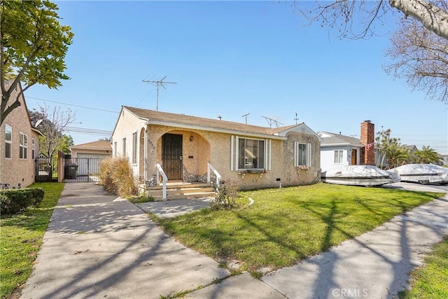 view of front of property with a front yard, fence, a gate, and stucco siding