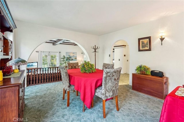 carpeted dining room featuring arched walkways