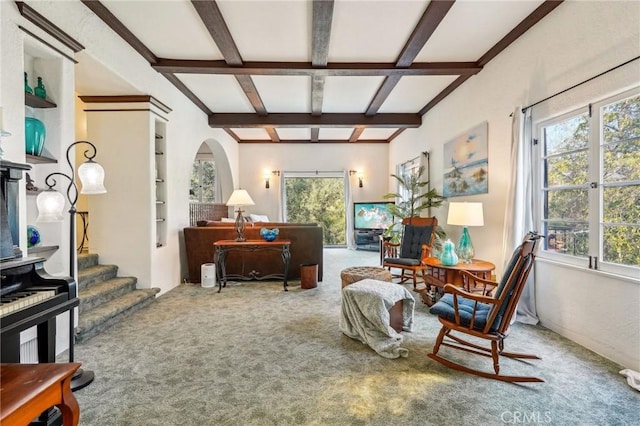 living area featuring carpet, beam ceiling, arched walkways, and stairs