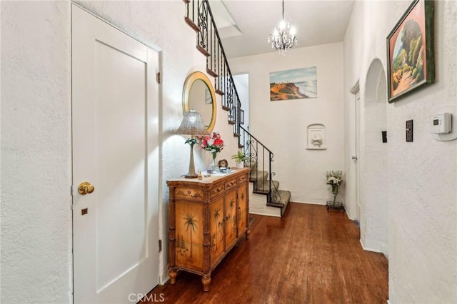 interior space featuring dark wood-style floors, a textured wall, stairs, and a chandelier