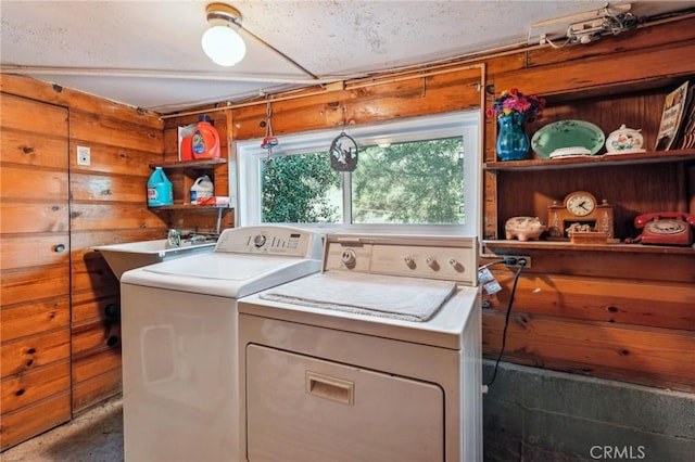 washroom with laundry area, washer and clothes dryer, a sink, and wooden walls