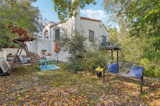 rear view of property featuring a patio area, a tiled roof, stairway, and stucco siding