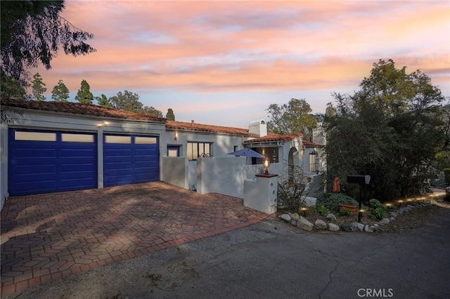 mediterranean / spanish home with a garage, decorative driveway, and stucco siding