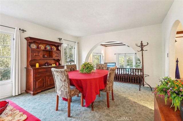 dining room with arched walkways and light carpet