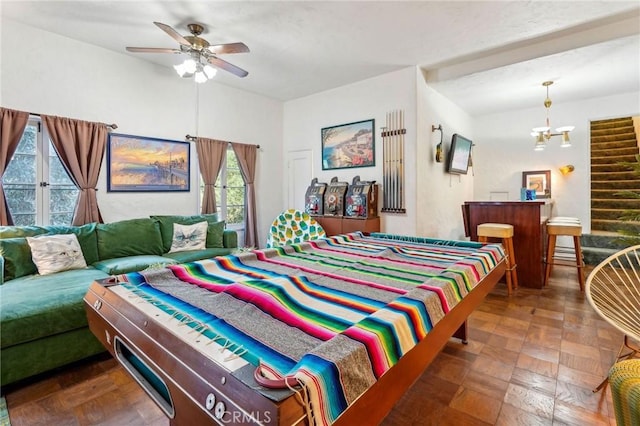 bedroom with multiple windows and ceiling fan with notable chandelier