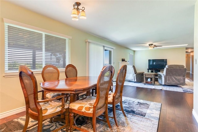 dining area featuring dark wood finished floors, baseboards, and ceiling fan with notable chandelier