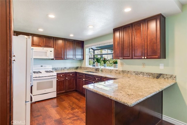 kitchen with dark wood-type flooring, a sink, light stone countertops, white appliances, and a peninsula