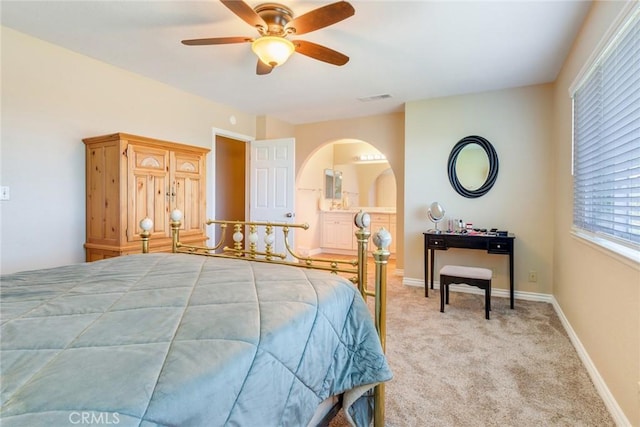 bedroom with baseboards, visible vents, arched walkways, light colored carpet, and ceiling fan