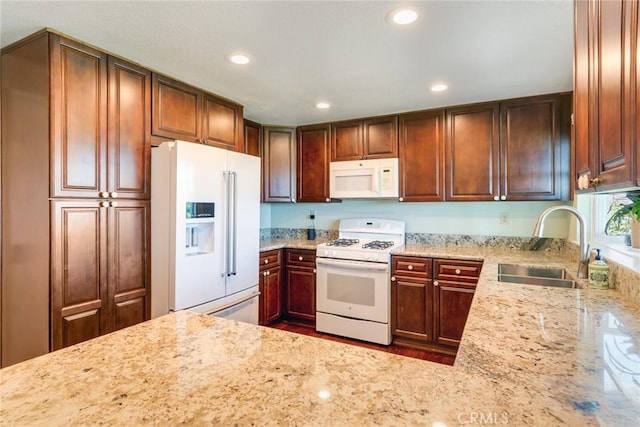 kitchen featuring light stone counters, recessed lighting, white appliances, and a sink