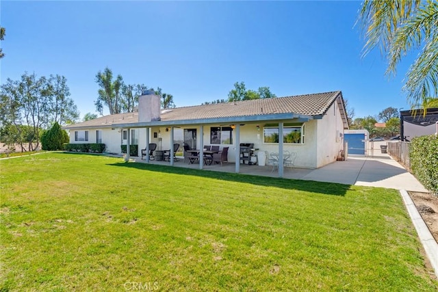 rear view of house featuring a patio, fence, a lawn, a gate, and stucco siding