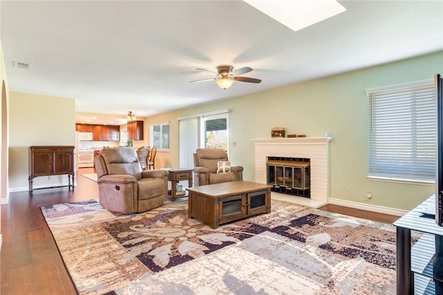 living area with a fireplace, wood finished floors, visible vents, and baseboards