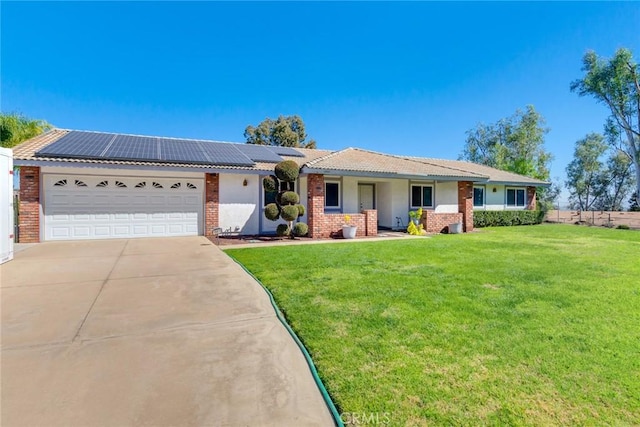 ranch-style home with driveway, a garage, a front yard, roof mounted solar panels, and brick siding