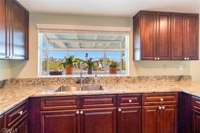 kitchen featuring reddish brown cabinets, a healthy amount of sunlight, and a sink