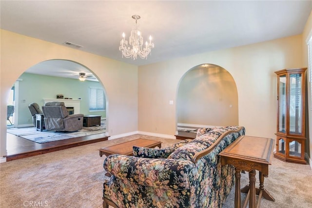 living area with arched walkways, a fireplace, visible vents, carpet flooring, and baseboards