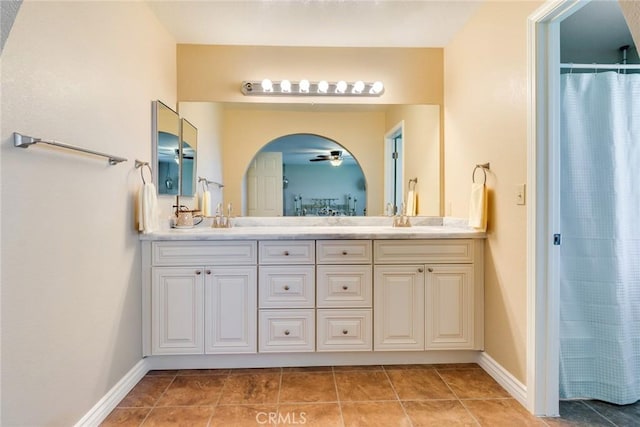 bathroom with double vanity, a ceiling fan, a sink, tile patterned flooring, and baseboards