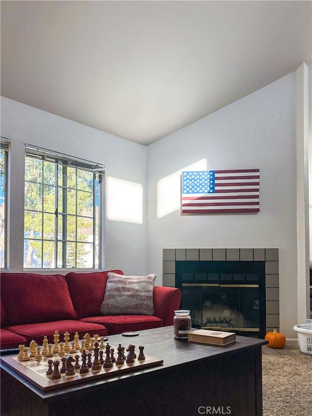 carpeted living area featuring a tiled fireplace