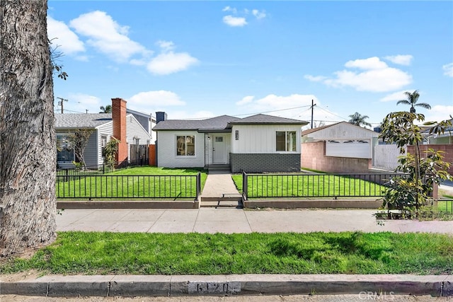 view of front of house with a fenced front yard, a front lawn, and brick siding