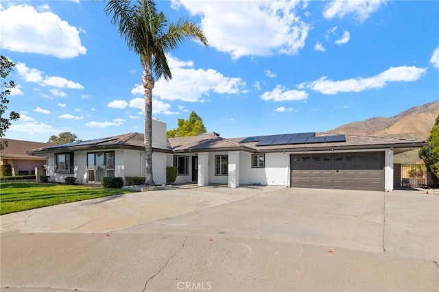 single story home with a mountain view, a garage, driveway, a chimney, and a front yard