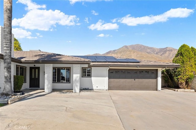 single story home with a mountain view and solar panels