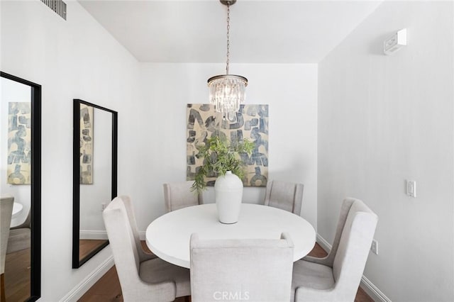 dining room featuring a chandelier, dark wood finished floors, visible vents, and baseboards