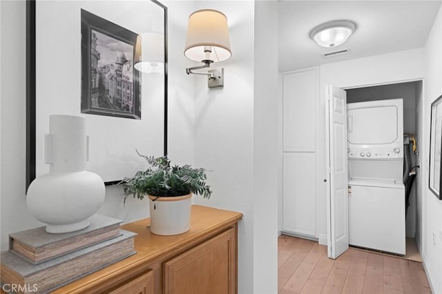 bathroom with stacked washer and dryer, visible vents, and wood finished floors