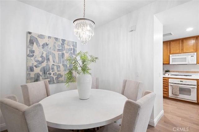 dining room featuring light wood-type flooring, a notable chandelier, and recessed lighting