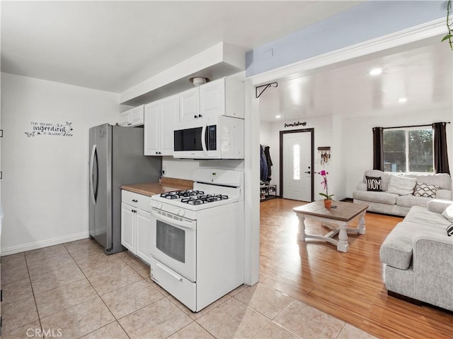 kitchen featuring light tile patterned floors, light countertops, open floor plan, white cabinets, and white appliances