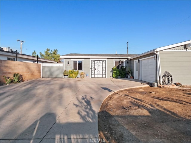 view of front facade with concrete driveway, an attached garage, and fence